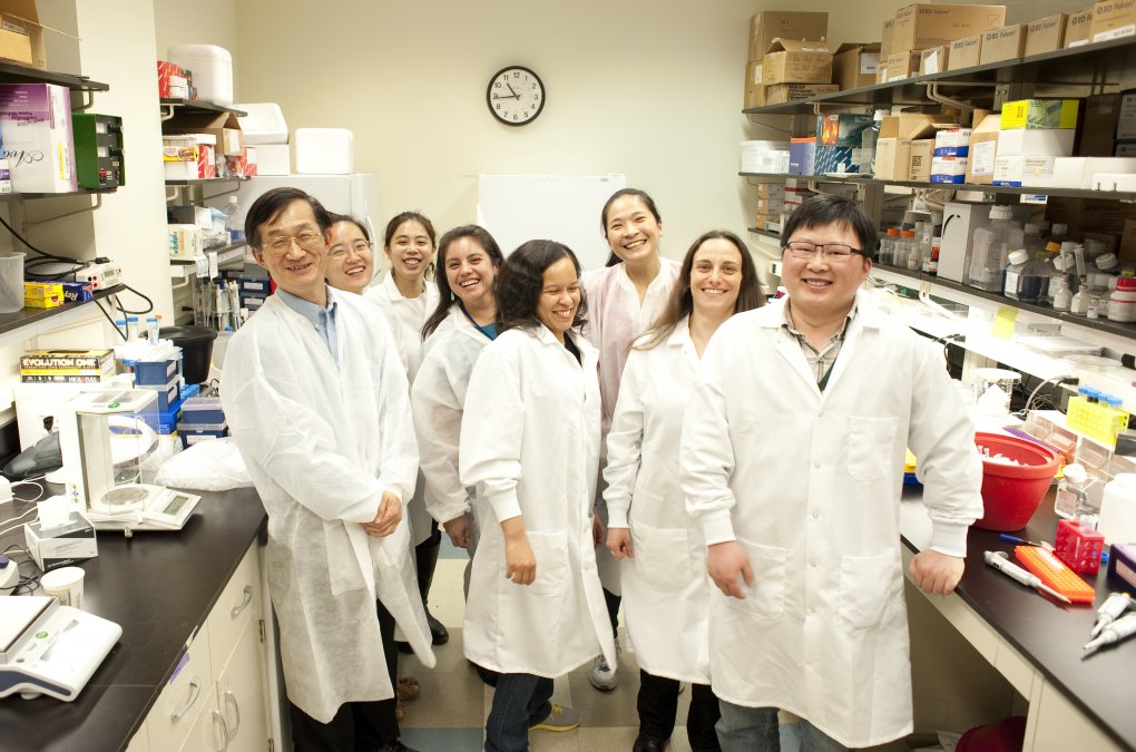A group of young scientists in a lab wearing white lab coats