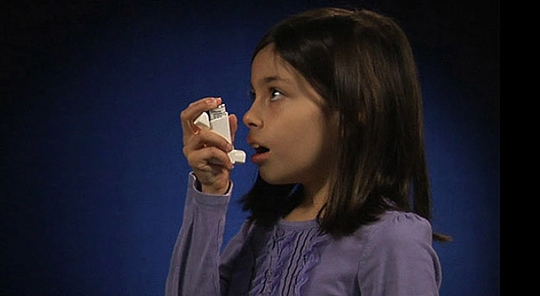 A young girl using an inhaler
