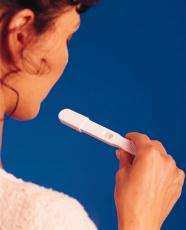 Fotografía de una mujer viendo el resultado de una prueba de embarazo